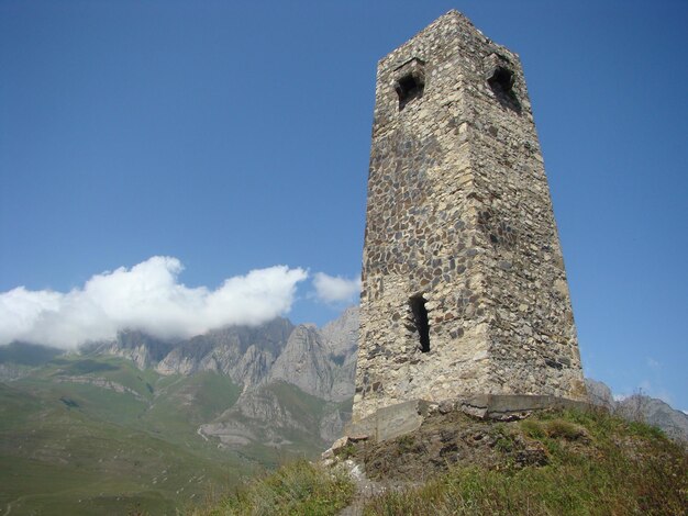 Ancient tower on caucasis with blue sky and mountauns background