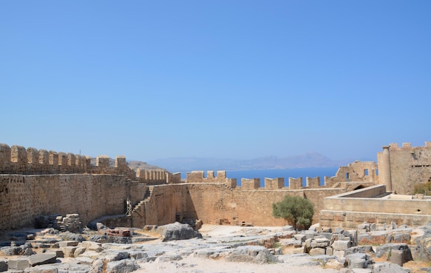 ancient wall of fortress with ruins and blue sky on horizon, Greece