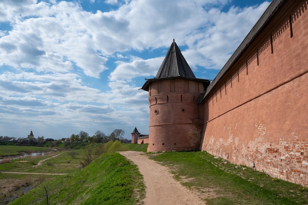 Ancient walls and towers of Suzdal Kremlin with walking path around and country landscape