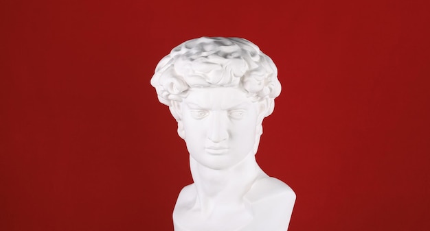 ancient white plaster head sculpture on a red background