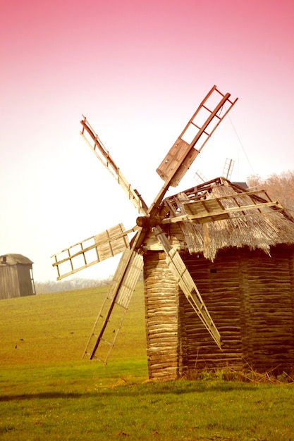 Photo ancient windmill on the field with pink filter