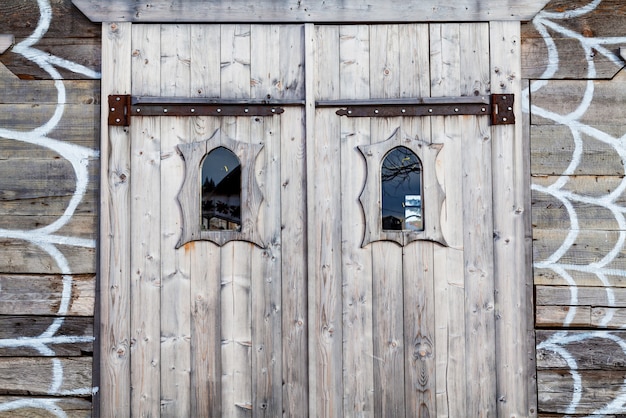 An ancient wooden door with small glass windows and decorative wooden frames.