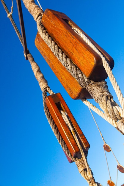 Ancient wooden pulleys of a sailing ship with knotted ropes against the sky