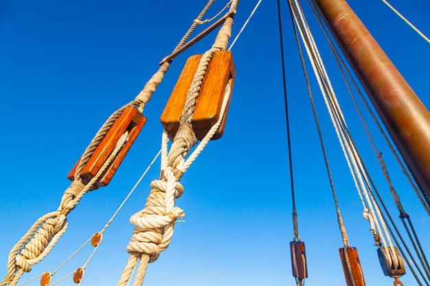 Ancient wooden pulleys of a sailing ship with knotted ropes against the sky