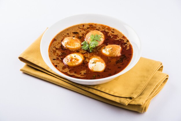 Anda Curry or Egg masala gravy, indian spicy food or recipe, served with Jeera Rice,roti or naan, selective focus. Over colourful or wooden table top