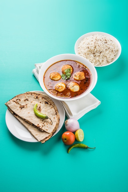 Anda Curry or Egg masala gravy, indian spicy food or recipe, served with Jeera Rice,roti or naan, selective focus. Over colourful or wooden table top