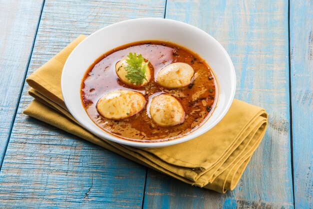 Anda Curry or Egg masala gravy, indian spicy food or recipe, served with Jeera Rice,roti or naan, selective focus. Over colourful or wooden table top