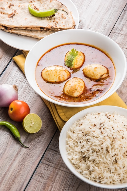 Anda Curry or Egg masala gravy, indian spicy food or recipe, served with Jeera Rice,roti or naan, selective focus. Over colourful or wooden table top