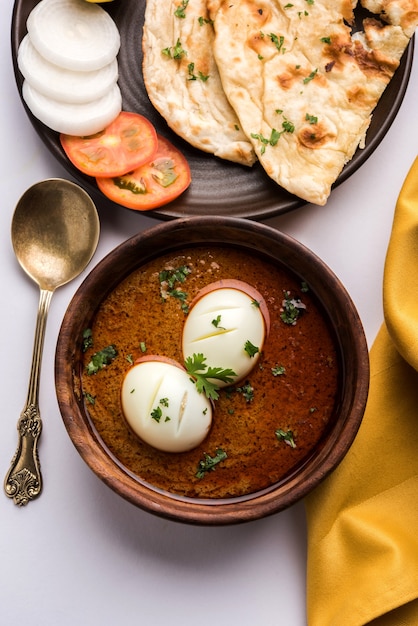 Anda Curry or Egg masala gravy, indian spicy food or recipe, served with roti or naan, selective focus