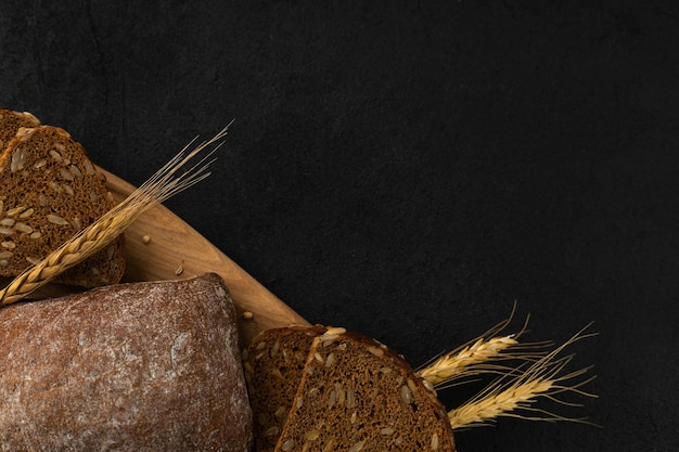 Ander brood op een houten snijplank roggebrood glutenvrije tarwe met granen op een zwarte achtergrond met ruimte voor tekst