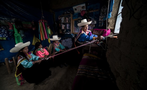 Foto andes latijns-amerikaanse moeder die haar meisjes de inca-techniek van het peruaanse tailleweven leert