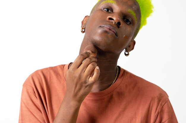 An androgynous black man posing putting on makeup LGTBI concept applying blusher white background