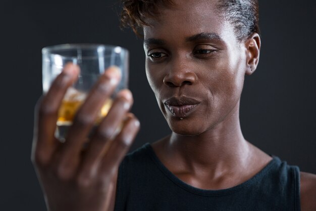 Photo androgynous man holding whiskey glass