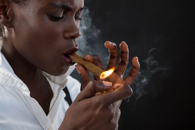 Androgynous man lighting a cigar