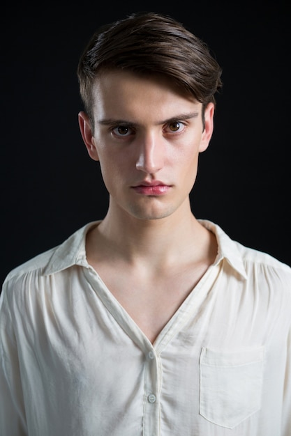 Androgynous man posing against grey wall