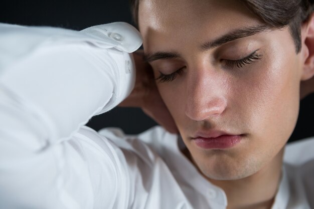 Androgynous man posing in open buttondown shirt with eyes closed