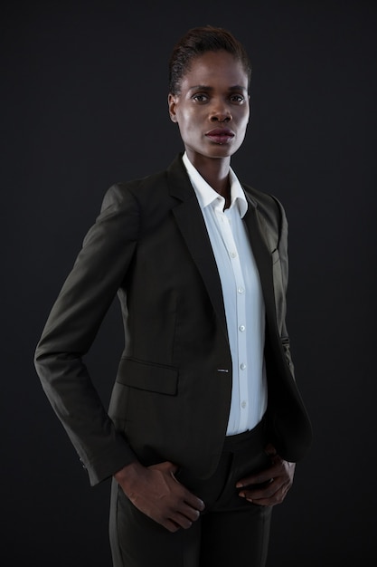 Androgynous man in suit posing against grey wall