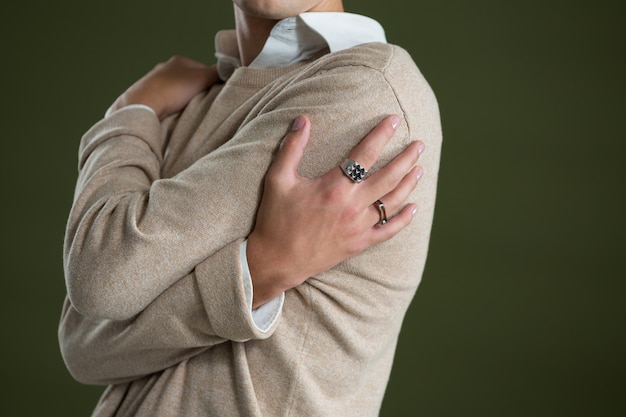 Androgynous man touching his body against green wall