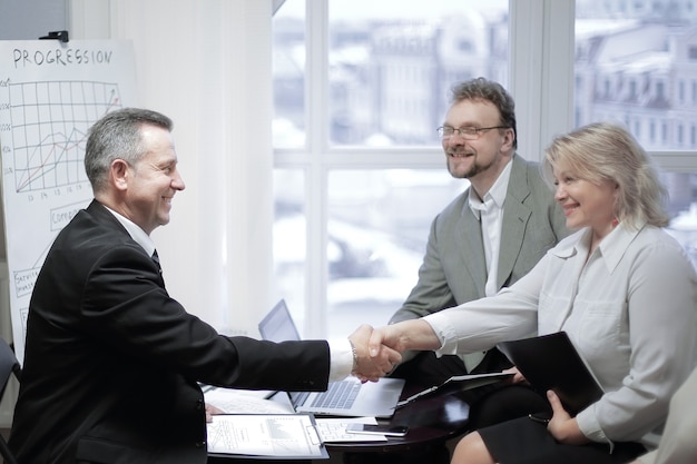 Andshake of a businessman and business woman at a meeting in the office