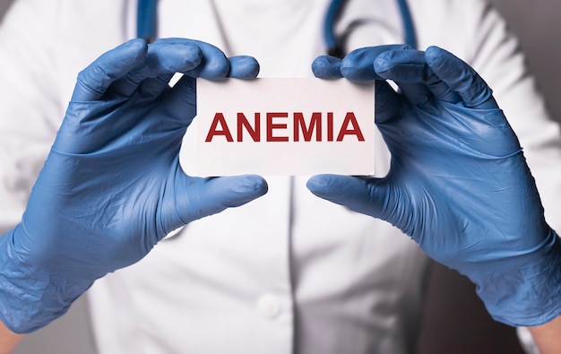 Anemia word on paper in doctor hand in gloves close up