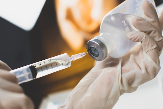 Anesthesiologist Doctors hand inject syringe into normal saline solution (NSS) bottle.