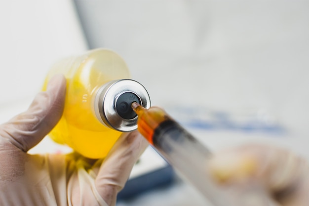 Foto anesthesioloog artsen injecteren de injectiespuit met de hand in een fles met normale zoutoplossing (nss).