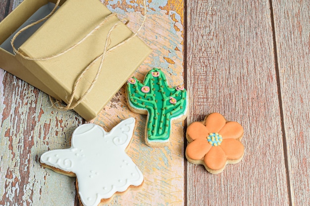 Angel, flower and cactus biscuits next to a small golden box with a string of string.