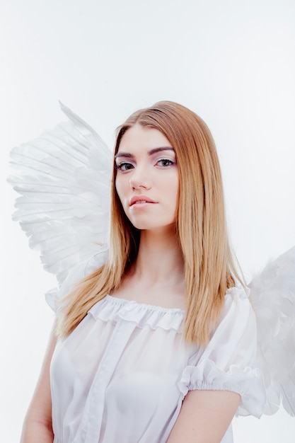 Photo an angel from heaven. young, wonderful blonde girl in the image of an angel with white wings. portrait close-up