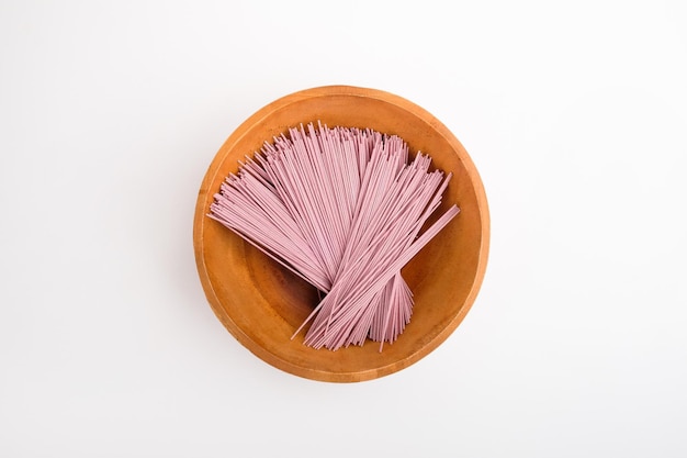 Foto angel hair paarse pasta in een houten kom op witte achtergrond