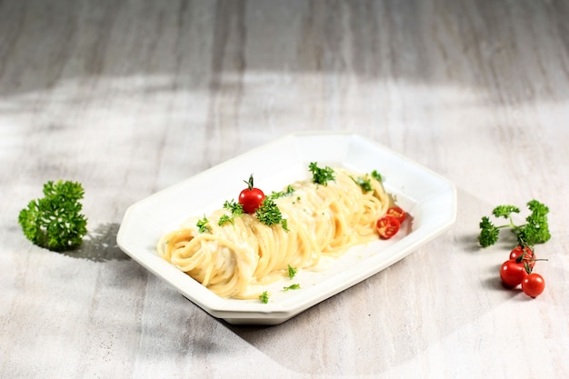 Паста Angel Hair со сливочным соусом Карбонара, Спагетти Алла Карбонара с сыром Пармезан. Подается на прямоугольной тарелке