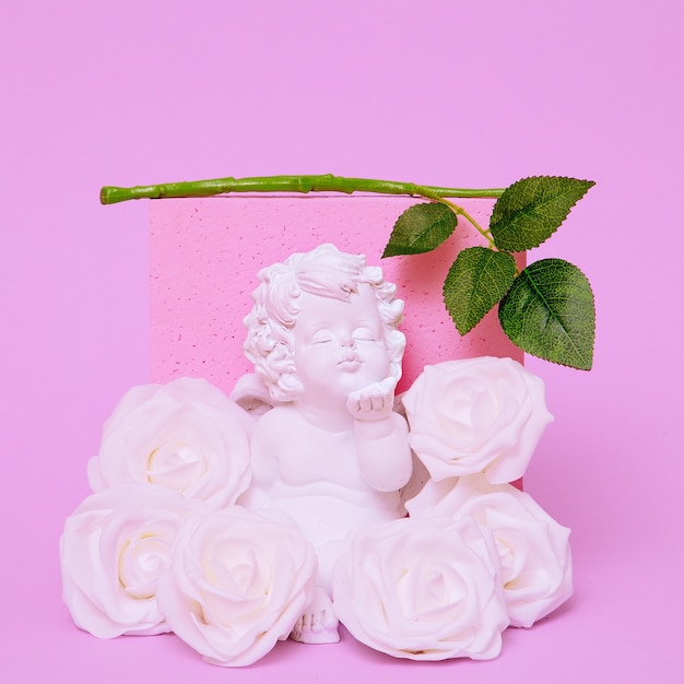 Angel in roses and pink background. Minimal flat lay art