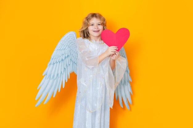 Photo angel with heart valentine angel little cupid child kid angel with angels wings isolated on yellow