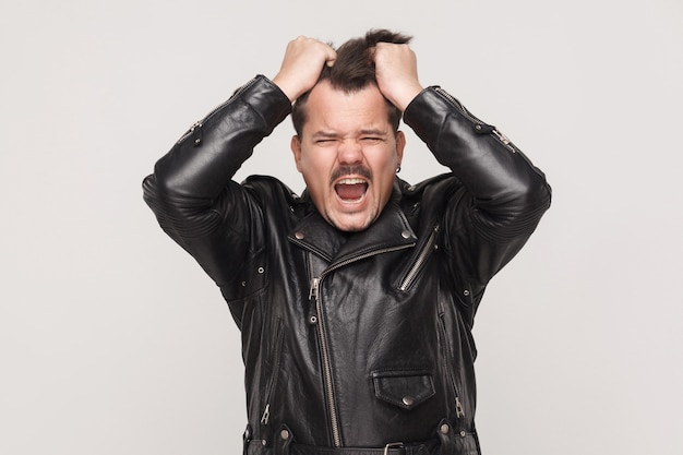 Anger man scream at camera and holding head. Studio shot