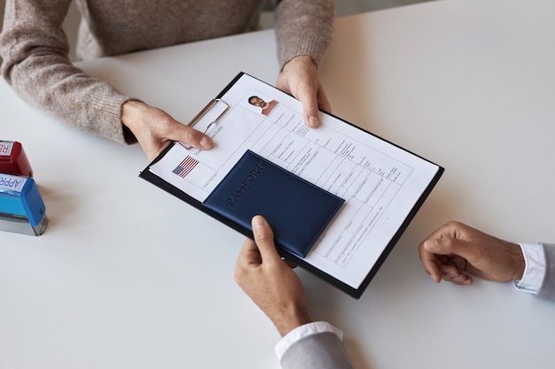 Above angle of filled form for visa request and passport being passed by man