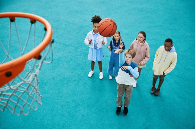 Above angle of intercultural schoolchildren playing basketball together