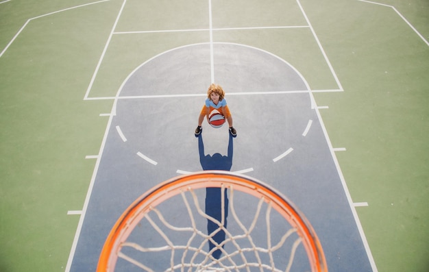 Angle view from on top of child playing basketball on playground