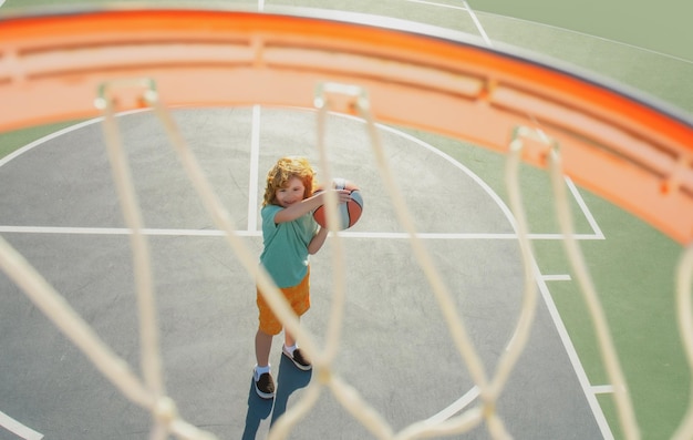 Угловой вид сверху летящего мяча на корзину от ребенка, играющего в баскетбол