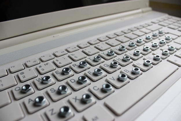 Angled side view of a computer keyboard with an iron nut on each button