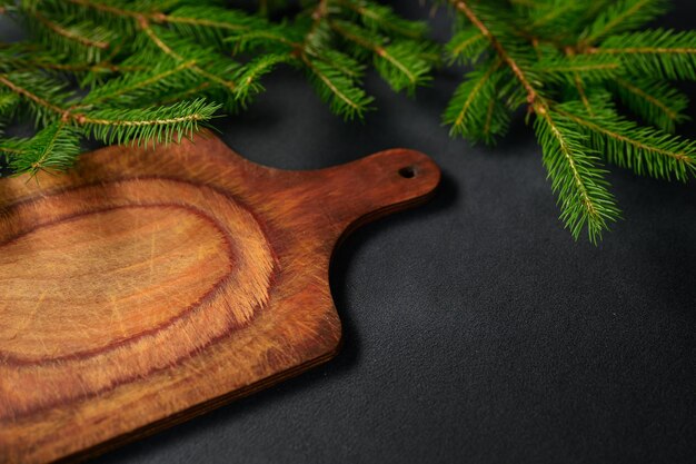 An angled view of Christmas layout with Fir branches and an Old Wooden Cutting Board in foreground