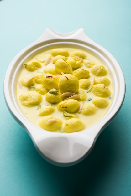 Angoori Rasmalai is een Indiaas dessert zoet met droog fruit en saffraan toppings, geserveerd in een kom op een humeurige achtergrond. selectieve focus