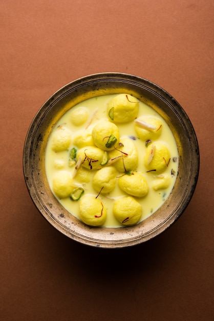 Angoori Rasmalai is een Indiaas dessert zoet met droog fruit en saffraan toppings, geserveerd in een kom op een humeurige achtergrond. selectieve focus