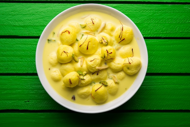 Angoori Rasmalai is een Indiaas dessert zoet met droog fruit en saffraan toppings, geserveerd in een kom op een humeurige achtergrond. selectieve focus