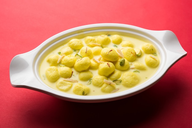 Angoori Rasmalai is an Indian dessert sweet with dry fruits and Saffron toppings, served in a bowl over moody background. selective focus