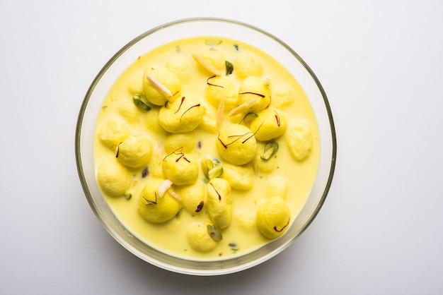 Angoori Rasmalai is an Indian dessert sweet with dry fruits and Saffron toppings, served in a bowl over moody background. selective focus