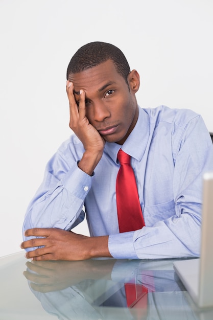 Angry Afro businessman with hand on face at desk