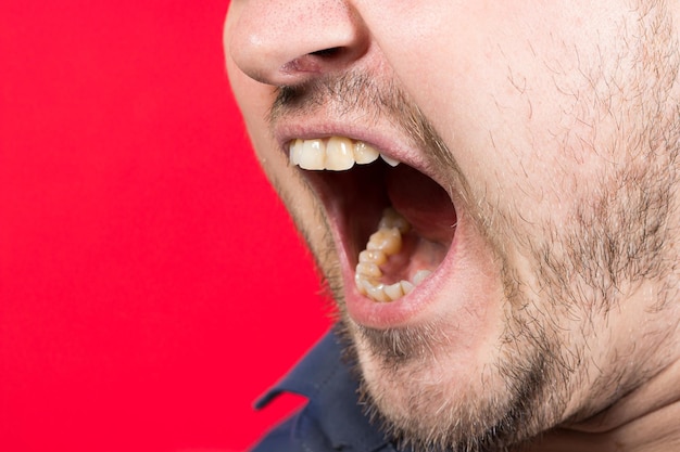 An angry aggressive man screams with mouth open