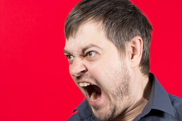 Photo an angry aggressive man screams with mouth open.