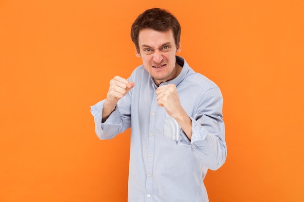 Angry aggressive man standing clenched fists and being ready to attack fighting looking at camera