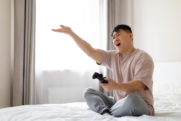 Angry asian man playing video games at home