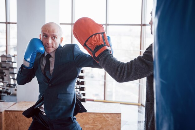 Photo an angry bald businessman beats a boxing pear in the gym concept of anger management